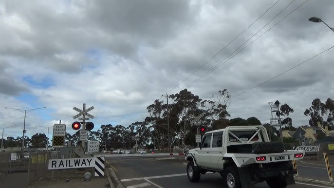 Boom gates lowering at the McClelland Avenue level crossing, Lara, with traffic queued