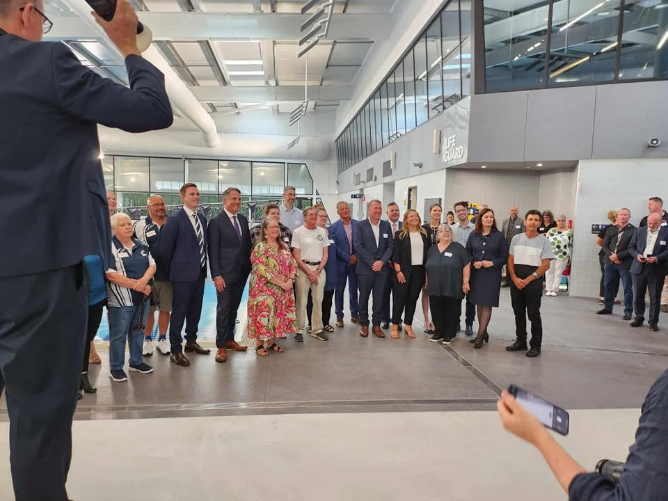 Officials and community members gathered beside the pool at the official opening
