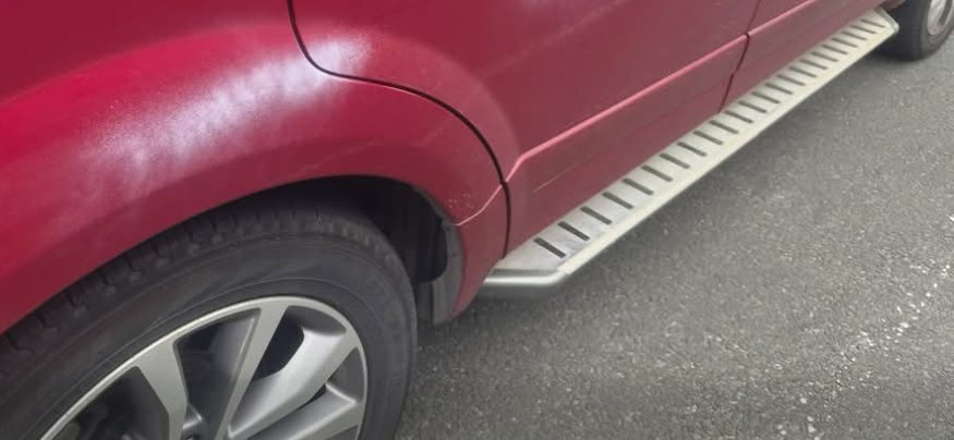 A red vehicle with light overspray visible along the lower side panels