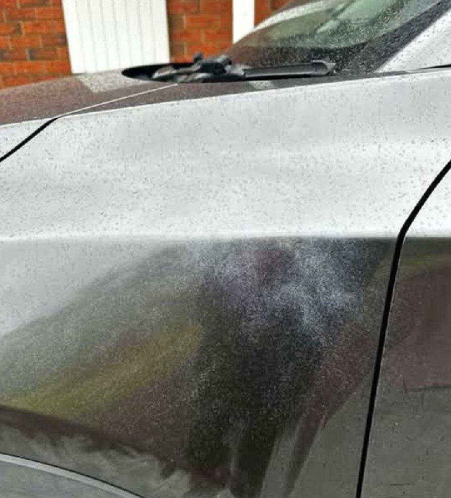 Close-up of a front guard showing a heavy band of spray paint mist across the panel
