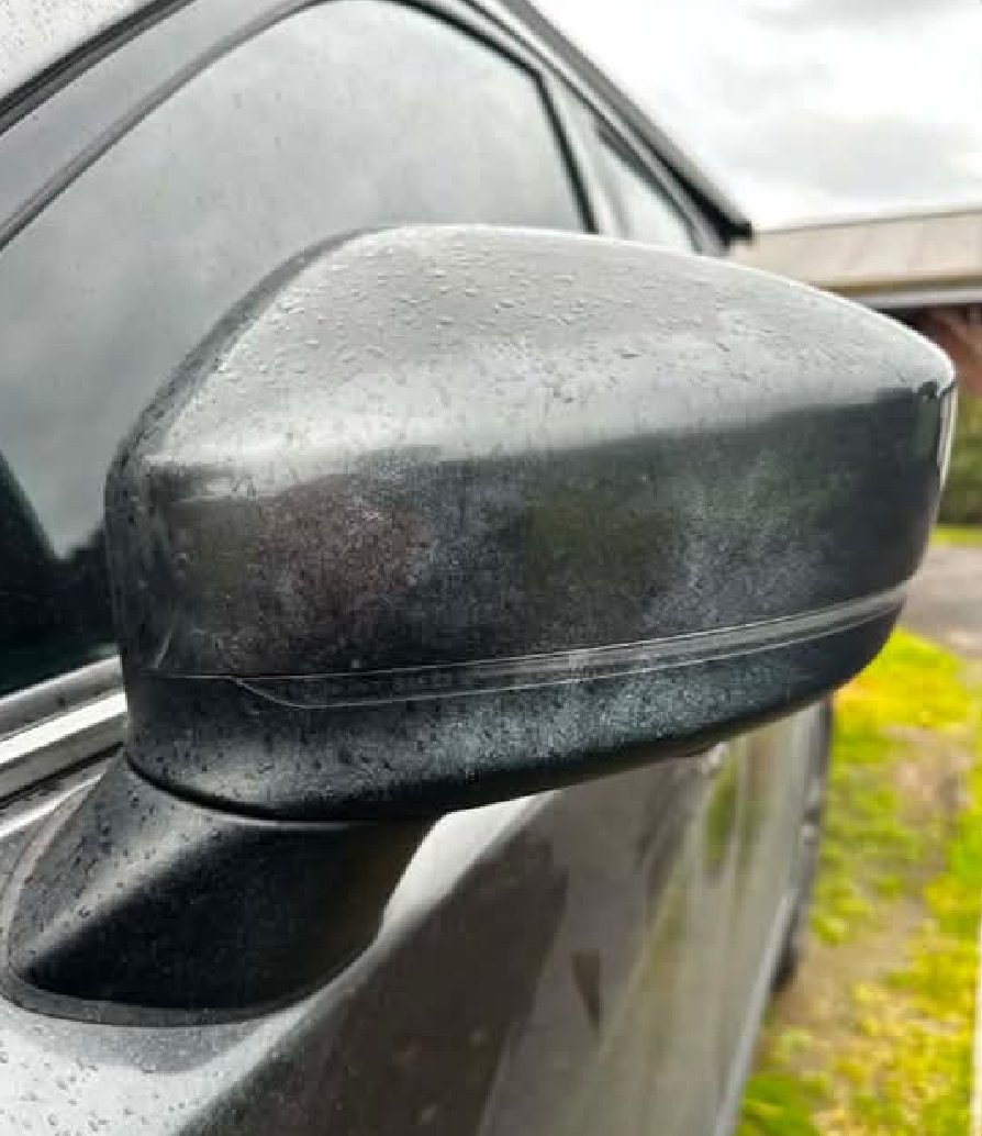 Close-up of a wing mirror and door with spray paint mist over the paintwork